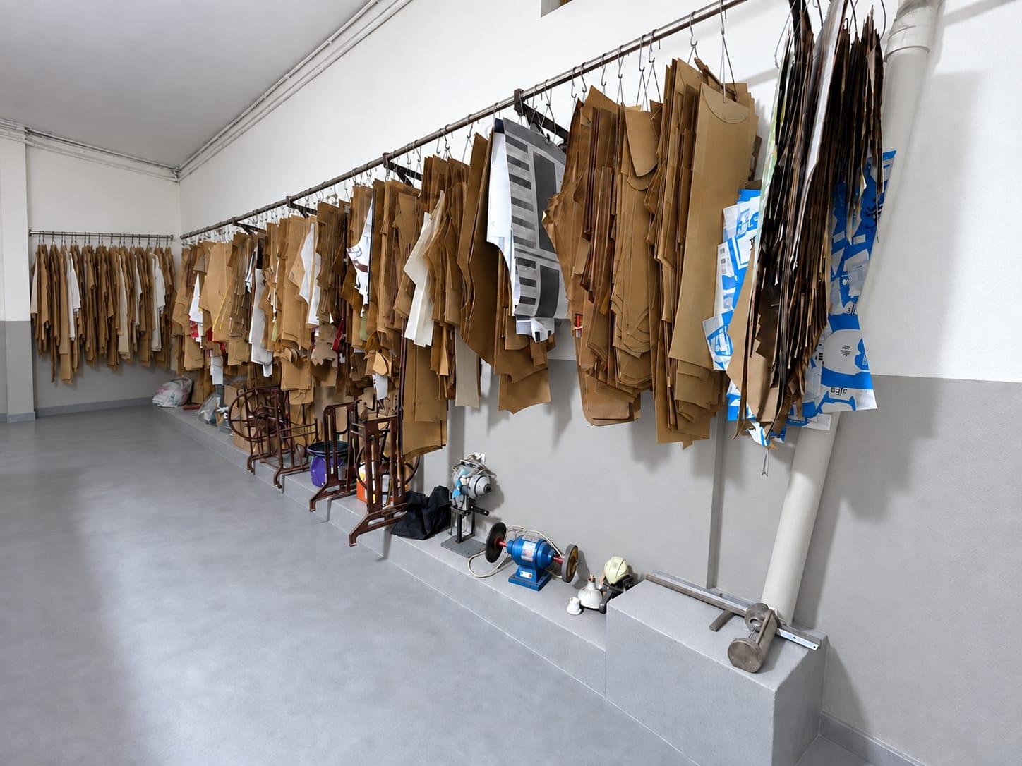 Paper garment patterns hanging in rows on rails along the pattern room wall