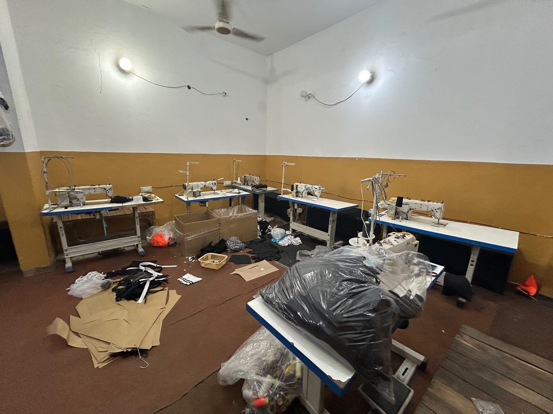 The stitching room with Juki industrial sewing machines on their tables and cut garment panels on the floor