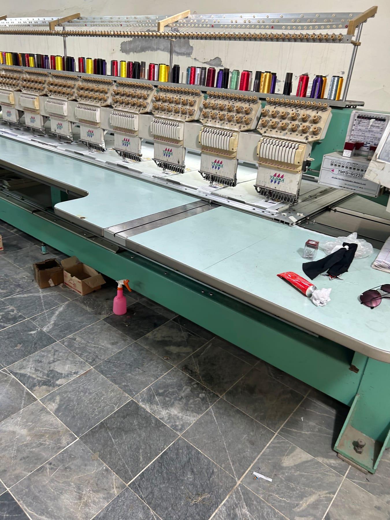 Tajima multi-head embroidery machine heads with thread cones in many colours above them